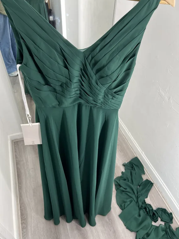 A dark green pleated occasion dress on a mannequin, back view