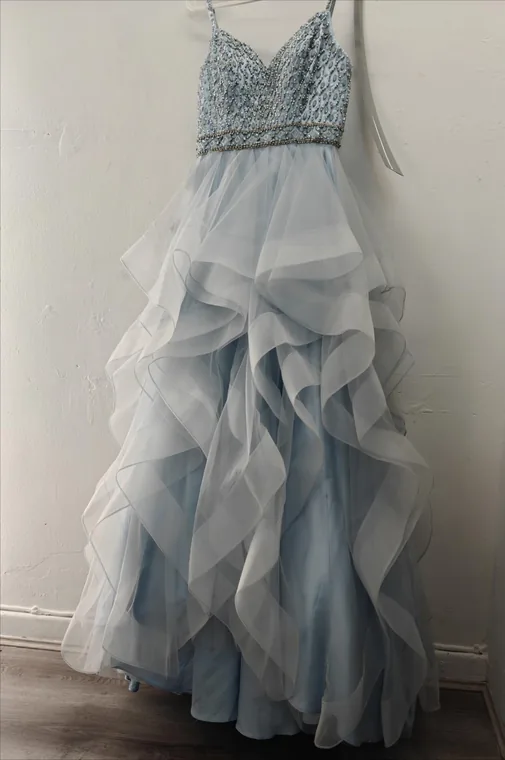 A pale blue beaded-bodice tulle gown hanging ready for collection