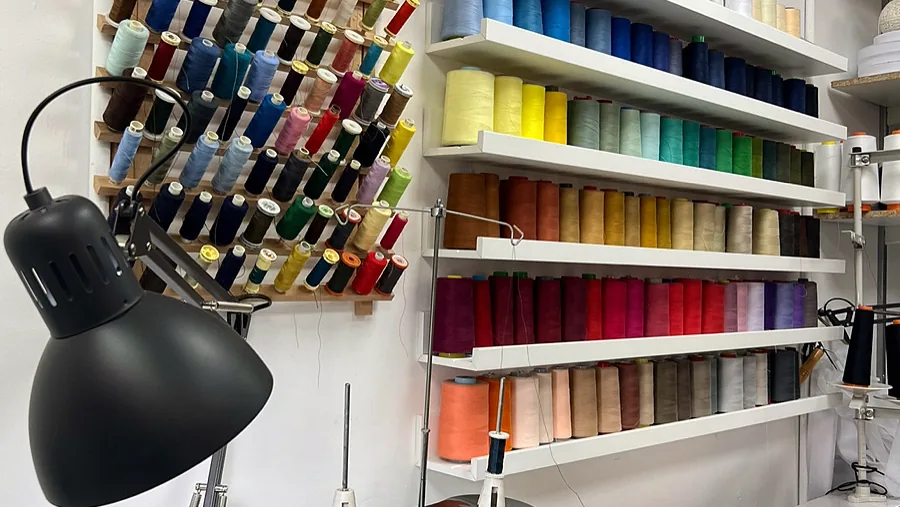 Wall of colour-sorted thread spools above the workbench