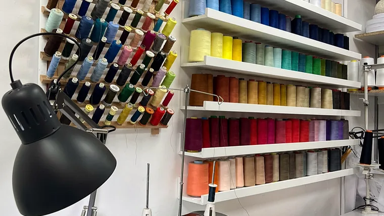 Wall of colour-sorted thread spools above the workbench